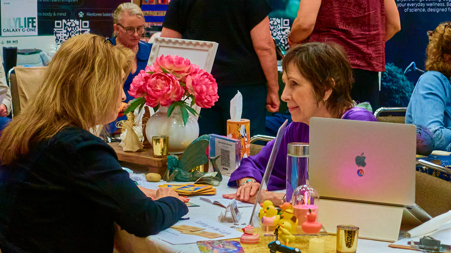 Visitor conversation with a welcoming table display at the Grapevine Wellness Expo, October 10–11, 2026.