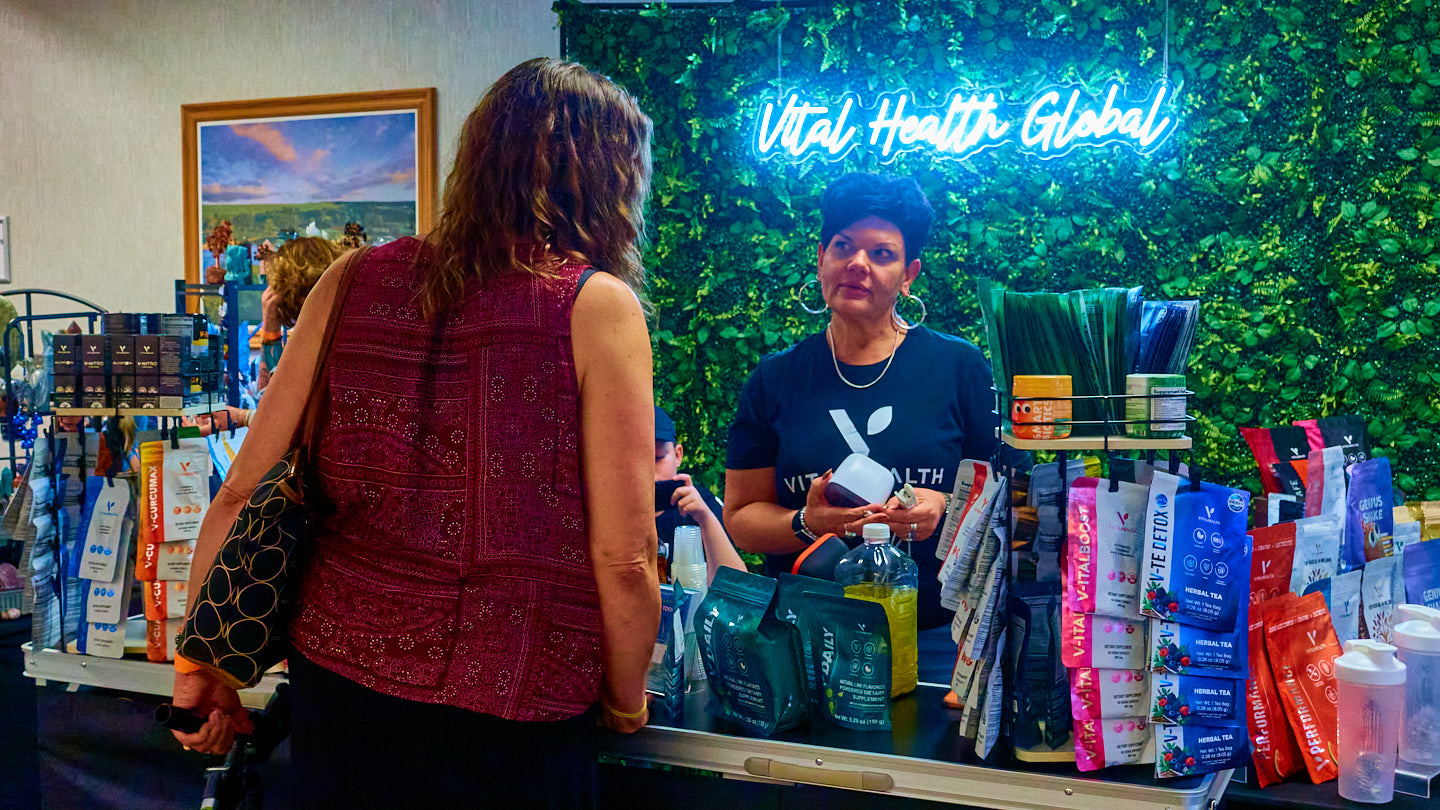 Visitor welcomed at a vivid market booth at the Grapevine Wellness Expo, October 10–11, 2026.